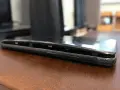 Il telefono è danneggiato, con lo schermo che si stacca dal corpo. Si vede la cornice interna e i pulsanti laterali.