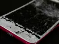 Cellulare caduto con schermo a righe, i frammenti di vetro coprono il tasto home.