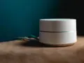 Dispositivo bianco cilindrico con una sottile linea luminosa, cavi sul lato. Sembra un router Wi-Fi non registrato sulla rete.