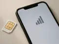 Scheda SIM accanto a uno smartphone con icona di segnale. Guida su come togliere la SIM dal telefono.