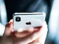 Mani che tengono un iPhone, con il logo Apple visibile. Perfetto per configurare l'APN Spusu e navigare.