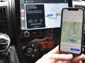 Navigazione in auto con collegamento al telefono. Mappa sul display dell'auto e sullo smartphone mostrano la stessa rotta.