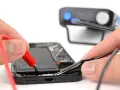 Mani che collegano cavi a un iPhone aperto, un esempio di riparazione fai-da-te con iFixit Italia.
