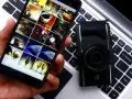 Smartphone con galleria foto su tastiera laptop, accanto a fotocamera. Guida rapida per scaricare le foto dal cellulare al pc.