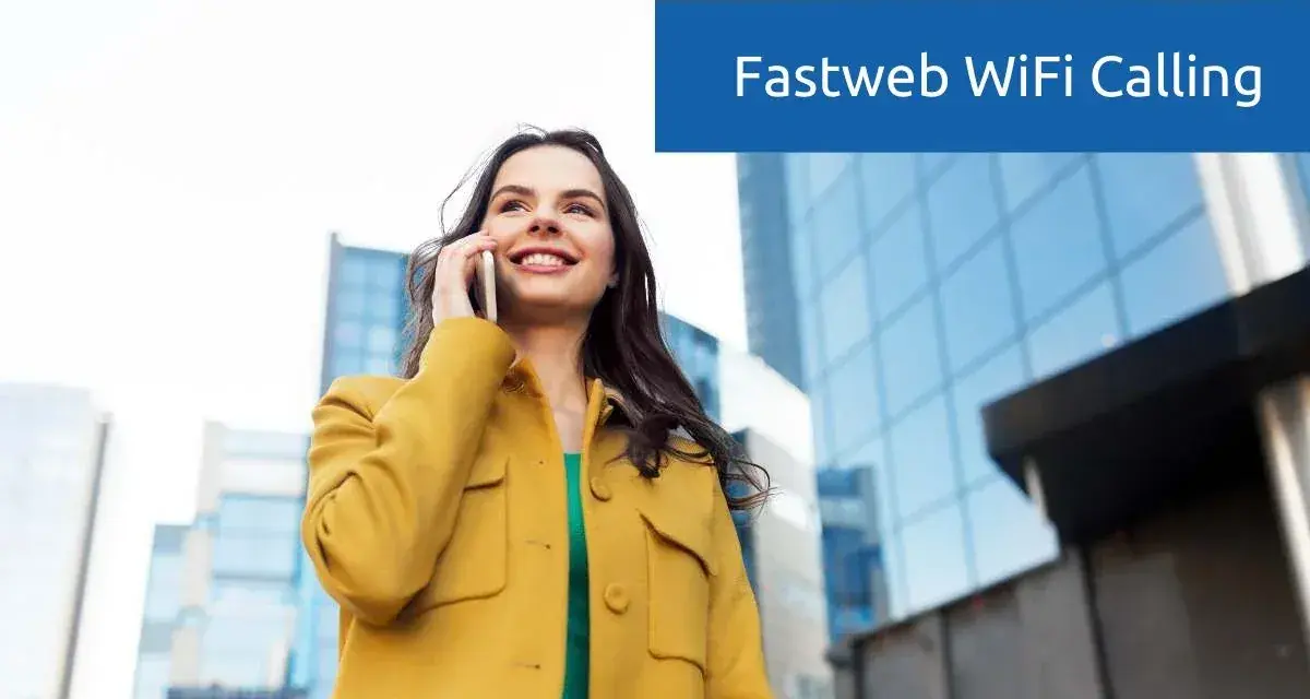 Donna sorridente parla al telefono con Fastweb WiFi Calling, con edifici moderni sullo sfondo.