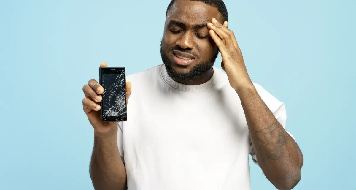 Uomo frustrato mostra il suo telefono con schermo rotto, il touch telefono non funziona.