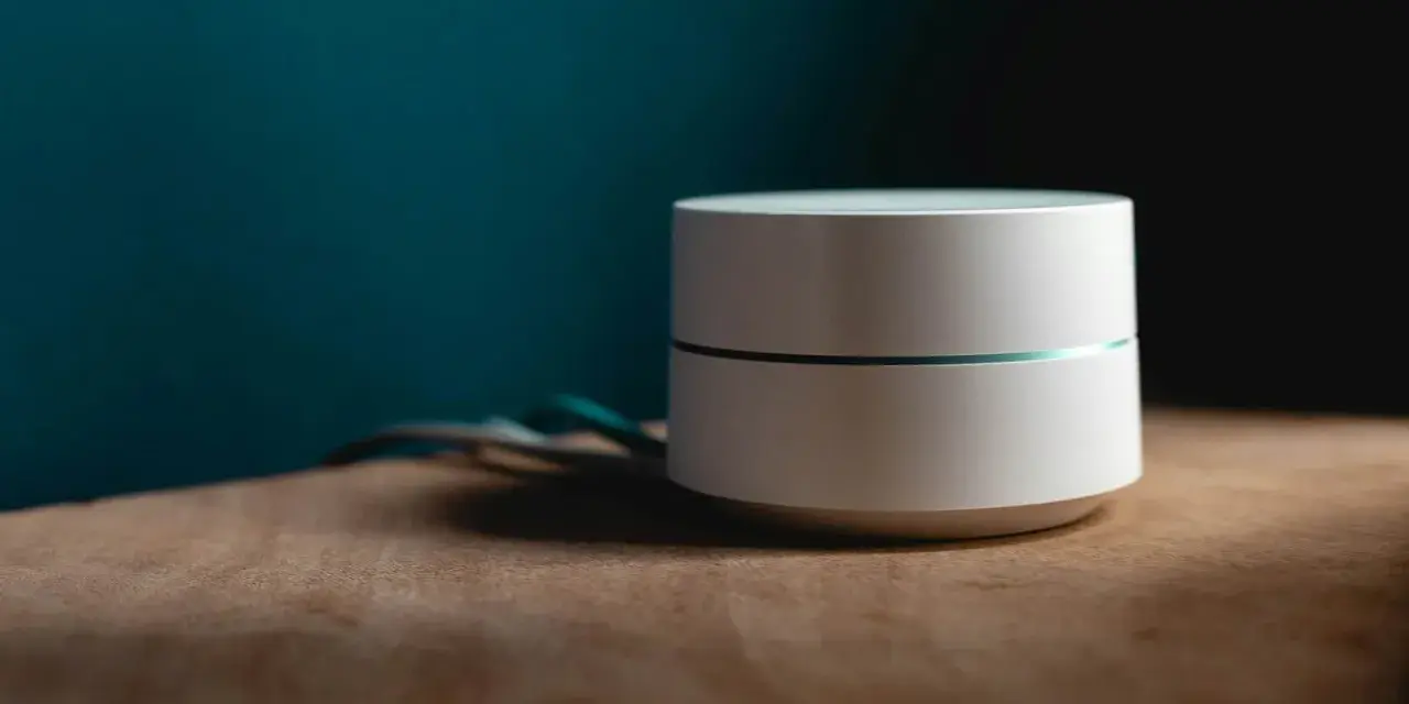 Dispositivo bianco cilindrico con una sottile linea luminosa, cavi sul lato. Sembra un router Wi-Fi non registrato sulla rete.