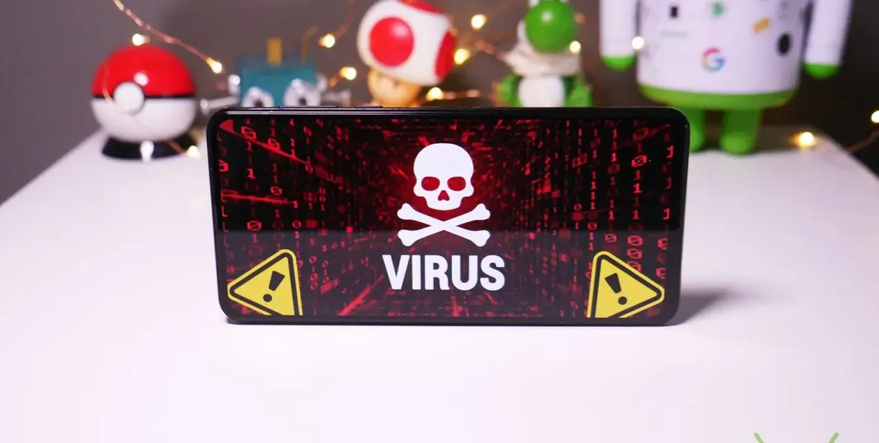 Schermo di un telefono con avviso "VIRUS" e teschio. Sullo sfondo, pupazzi di Android e Pokémon, con lucine.