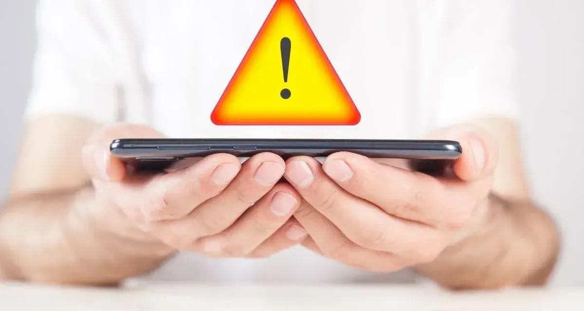 Mani tengono uno smartphone con un segnale di avvertimento giallo sopra. Problema di connessione: iliad non registrato sulla rete.