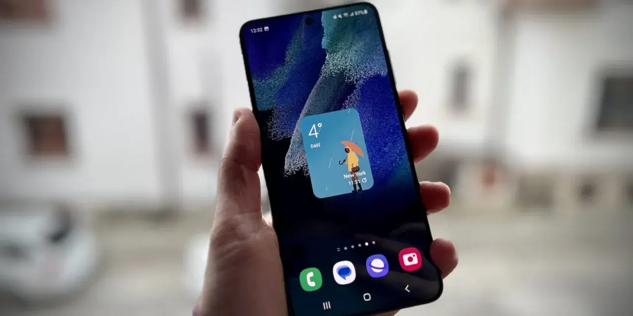 Un widget schermata di blocco Samsung mostra il meteo a New York: 4 gradi e pioggia con un ombrello giallo.