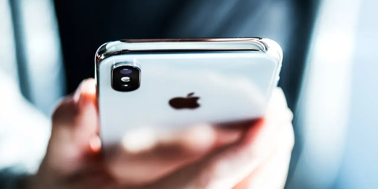 Mani che tengono un iPhone, con il logo Apple visibile. Perfetto per configurare l'APN Spusu e navigare.