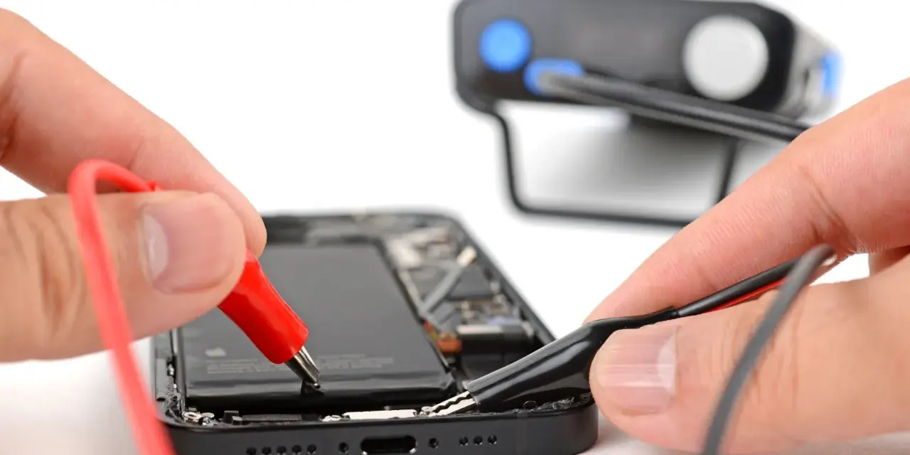 Mani che collegano cavi a un iPhone aperto, un esempio di riparazione fai-da-te con iFixit Italia.