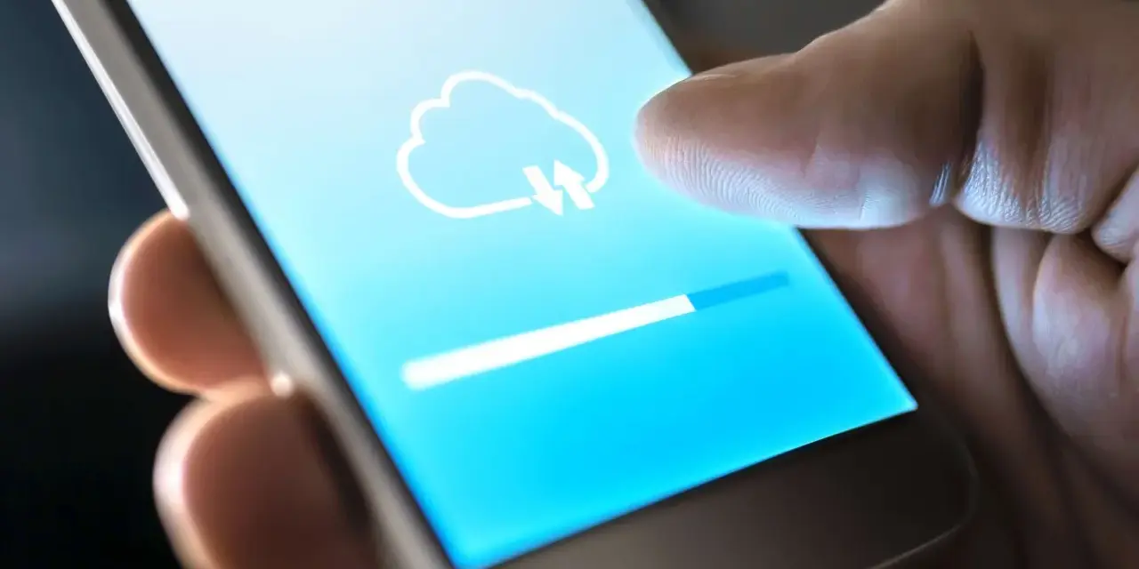 Dito cos'è il backup del cellulare: un'icona di nuvola con frecce indica il caricamento dei dati su uno smartphone, con una barra di avanzamento.