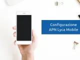 Configurazione APN Lycamobile Italia: mano che tiene uno smartphone bianco con schermo nero, su sfondo bianco con graffette.