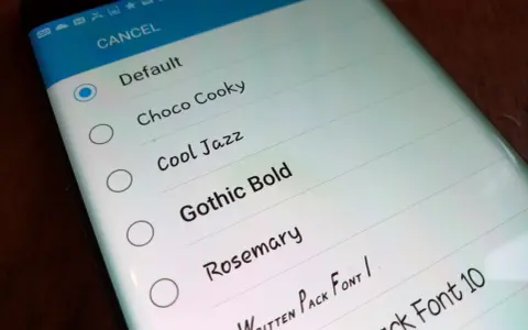 Schermata del telefono che mostra come cambiare scrittura sul telefono, con opzioni come "Default", "Choco Cooky" e "Gothic Bold".