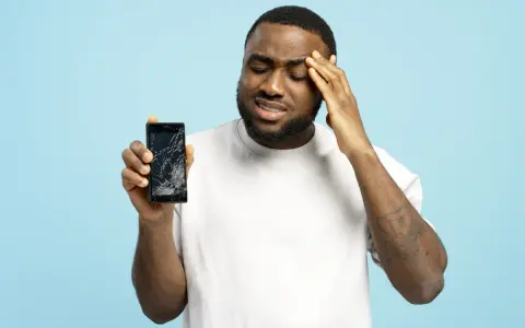 Uomo frustrato mostra il suo telefono con schermo rotto, il touch telefono non funziona.