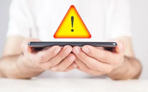 Mani tengono uno smartphone con un segnale di avvertimento giallo sopra. Problema di connessione: iliad non registrato sulla rete.