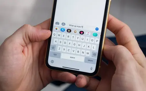Mani che tengono uno smartphone. La tastiera mostra come togliere la maiuscola per scrivere "What up man??".