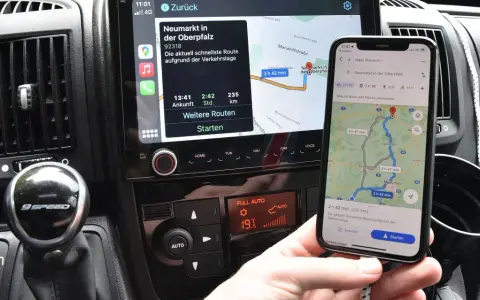 Navigazione in auto con collegamento al telefono. Mappa sul display dell'auto e sullo smartphone mostrano la stessa rotta.