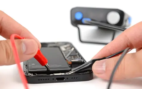 Mani che collegano cavi a un iPhone aperto, un esempio di riparazione fai-da-te con iFixit Italia.