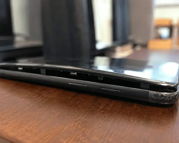 Il telefono è danneggiato, con lo schermo che si stacca dal corpo. Si vede la cornice interna e i pulsanti laterali.