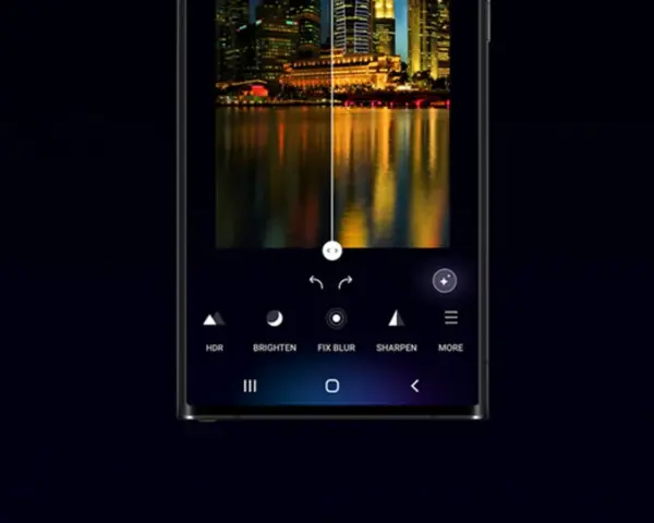 Interfaccia di editing foto su smartphone, con un paesaggio urbano notturno diviso a metà. L'opzione "galaxy enhance-x" migliora la nitidezza e i colori.
