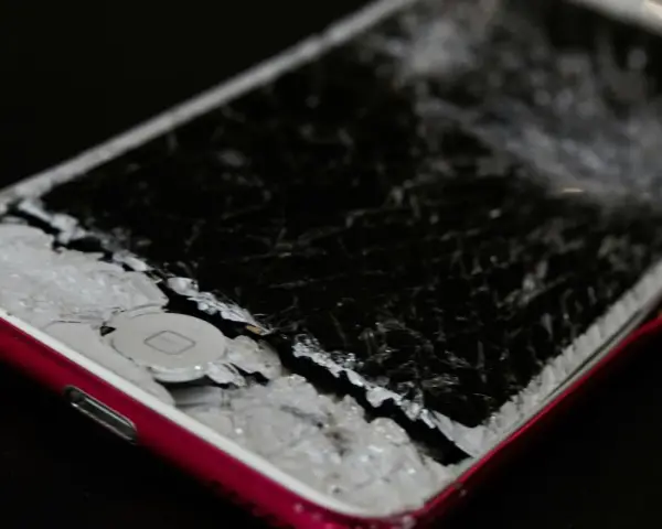 Cellulare caduto con schermo a righe, i frammenti di vetro coprono il tasto home.