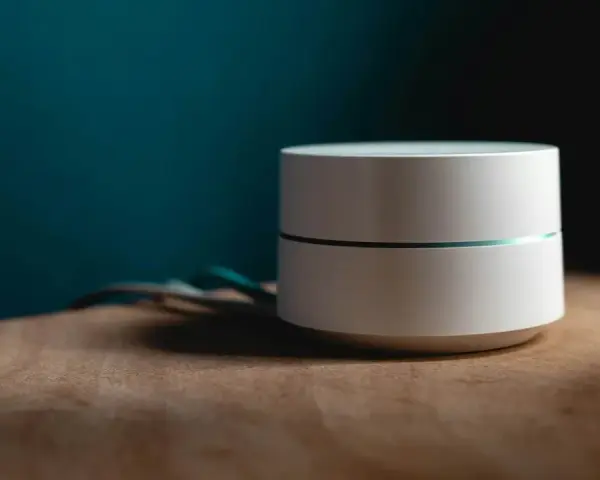 Dispositivo bianco cilindrico con una sottile linea luminosa, cavi sul lato. Sembra un router Wi-Fi non registrato sulla rete.