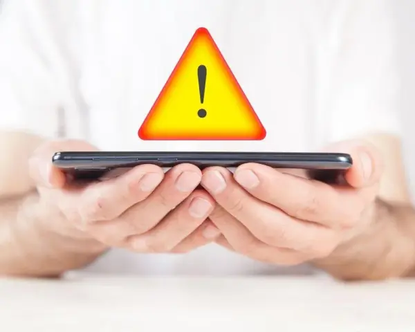 Mani tengono uno smartphone con un segnale di avvertimento giallo sopra. Problema di connessione: iliad non registrato sulla rete.