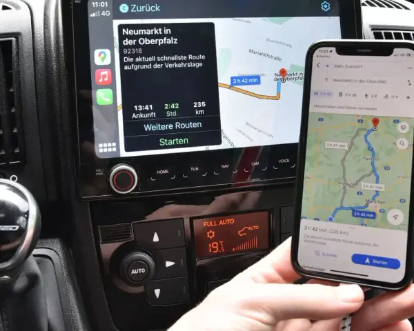 Navigazione in auto con collegamento al telefono. Mappa sul display dell'auto e sullo smartphone mostrano la stessa rotta.