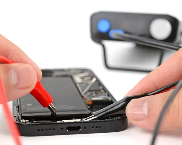 Mani che collegano cavi a un iPhone aperto, un esempio di riparazione fai-da-te con iFixit Italia.