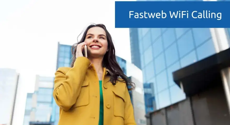 Donna sorridente parla al telefono con Fastweb WiFi Calling, con edifici moderni sullo sfondo.