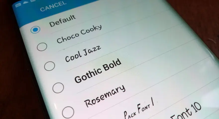 Schermata del telefono che mostra come cambiare scrittura sul telefono, con opzioni come "Default", "Choco Cooky" e "Gothic Bold".
