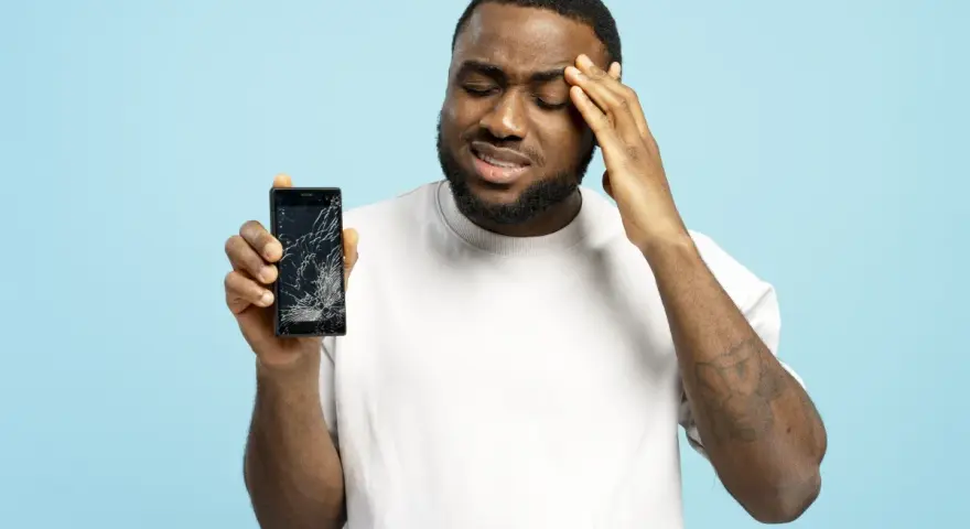 Uomo frustrato mostra il suo telefono con schermo rotto, il touch telefono non funziona.