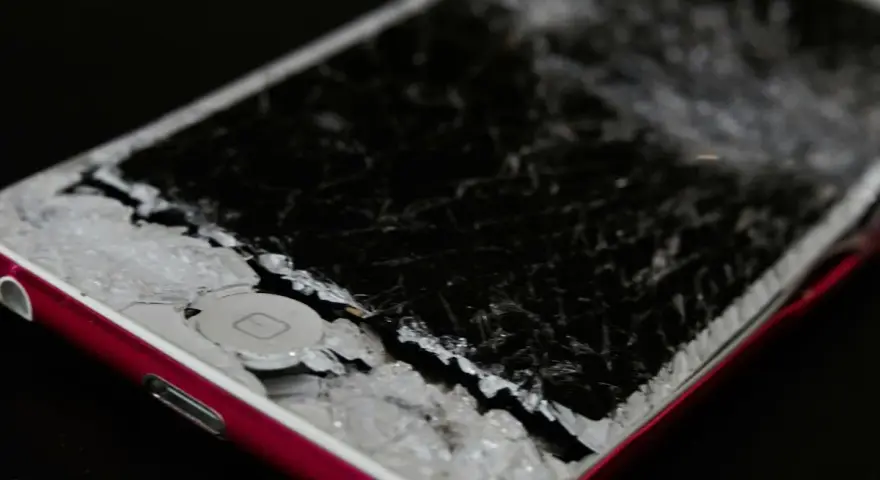 Cellulare caduto con schermo a righe, i frammenti di vetro coprono il tasto home.