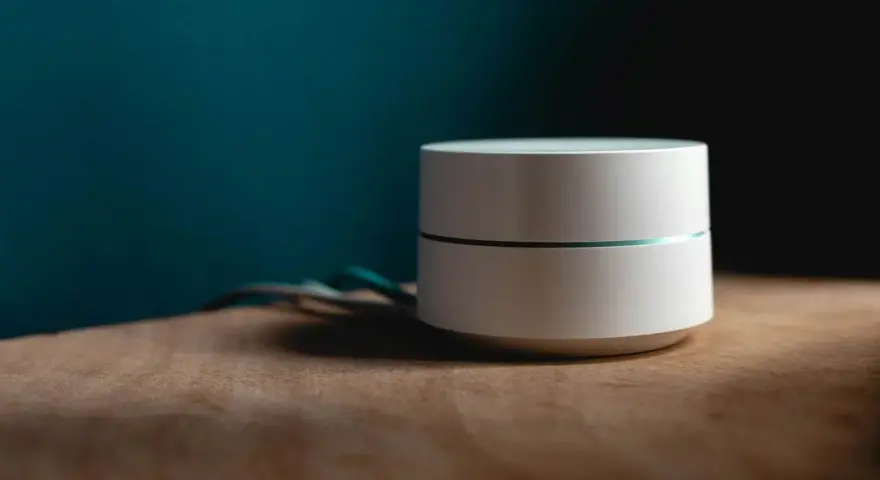 Dispositivo bianco cilindrico con una sottile linea luminosa, cavi sul lato. Sembra un router Wi-Fi non registrato sulla rete.