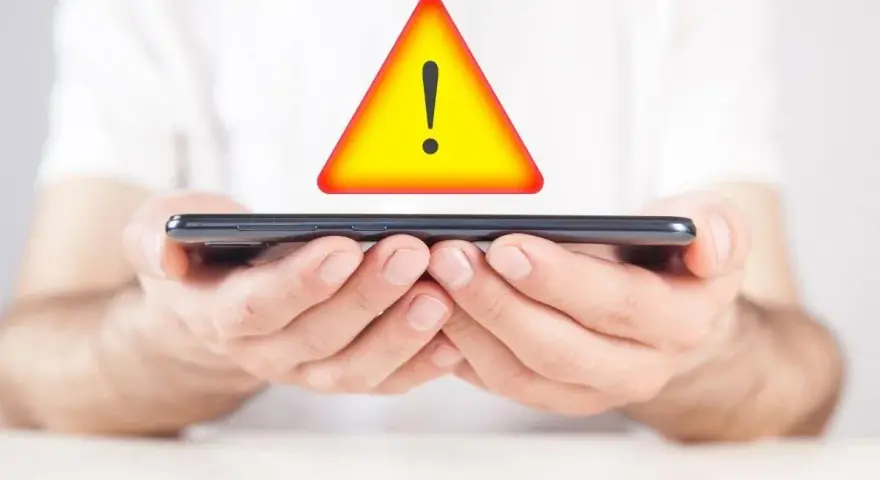 Mani tengono uno smartphone con un segnale di avvertimento giallo sopra. Problema di connessione: iliad non registrato sulla rete.
