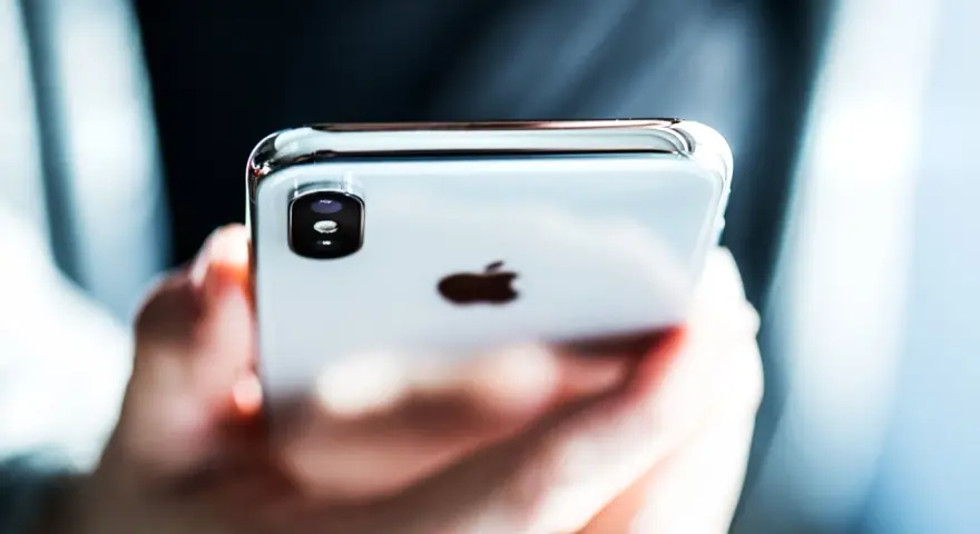 Mani che tengono un iPhone, con il logo Apple visibile. Perfetto per configurare l'APN Spusu e navigare.