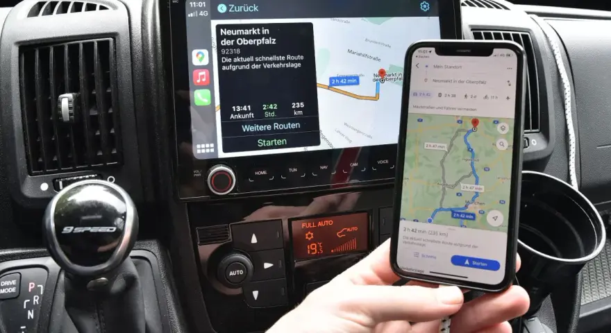 Navigazione in auto con collegamento al telefono. Mappa sul display dell'auto e sullo smartphone mostrano la stessa rotta.