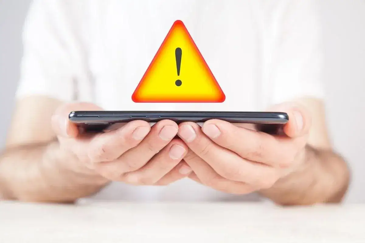 Mani che tengono uno smartphone con un segnale di avviso giallo sopra. Potrebbe indicare un problema di connessione, come 