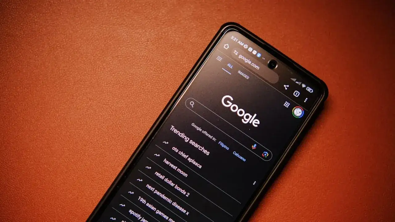 Smartphone con google sfondo nero, mostra la barra di ricerca e le ricerche di tendenza.
