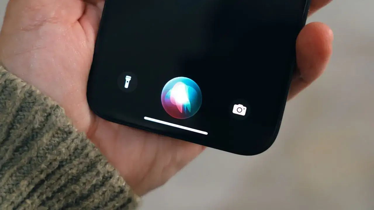Siri non risponde, il microfono dell'iPhone non funziona. La mano tiene il telefono con l'icona di Siri attiva.